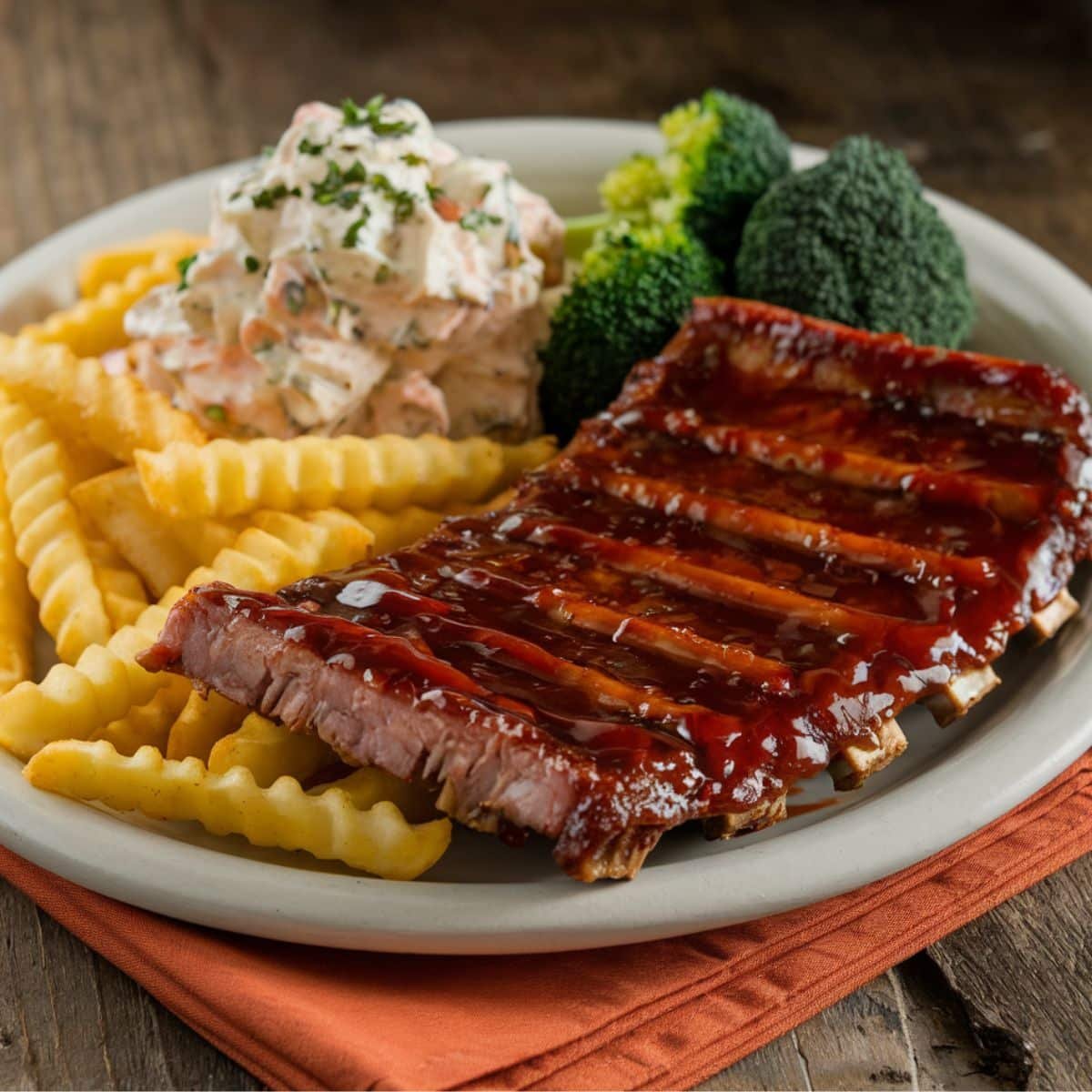 Juicy Boneless Beef Ribs glazed with barbecue sauce, served with crinkle-cut fries, creamy coleslaw, and steamed broccoli on a rustic plate – perfect for a delicious Boneless Beef Ribs Recipe meal.