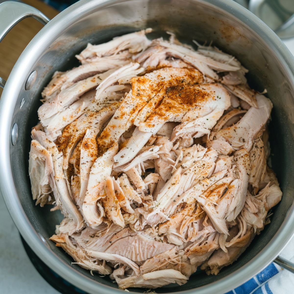 A pot filled with Instant Pot Shredded Chicken, seasoned with spices for extra flavor. This tender and juicy shredded chicken is perfect for meal prep, tacos, sandwiches, and salads. An easy, protein-packed recipe made in the Instant Pot.