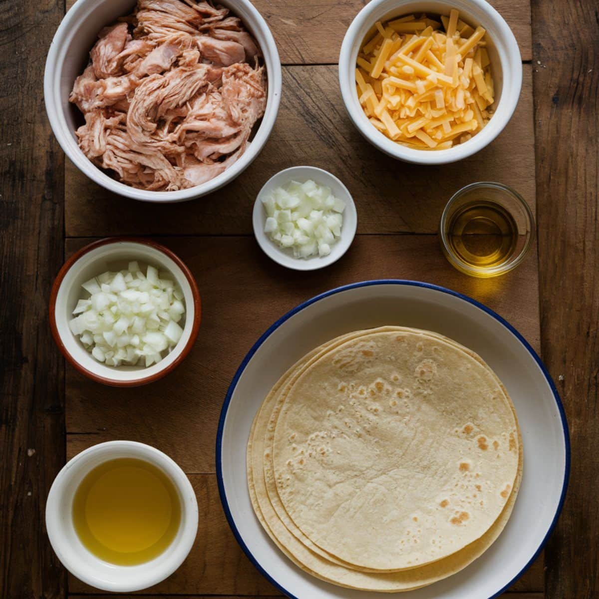 Key ingredients for Boulder's Enchilada Recipe including shredded chicken, shredded cheese, diced onions, corn tortillas, and vegetable oil, arranged neatly on a rustic wooden surface.