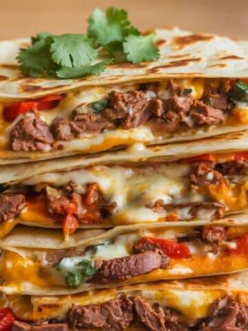 Close-up of a stack of mouthwatering Steak Quesadillas filled with seasoned steak, gooey melted cheese, and vibrant bell peppers, perfect for the ultimate Steak Quesadilla Recipe.