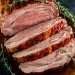 Tender and flavorful smoked pork loin slices with a golden-brown glaze, garnished with fresh thyme, perfect for a smoked pork loin recipe.