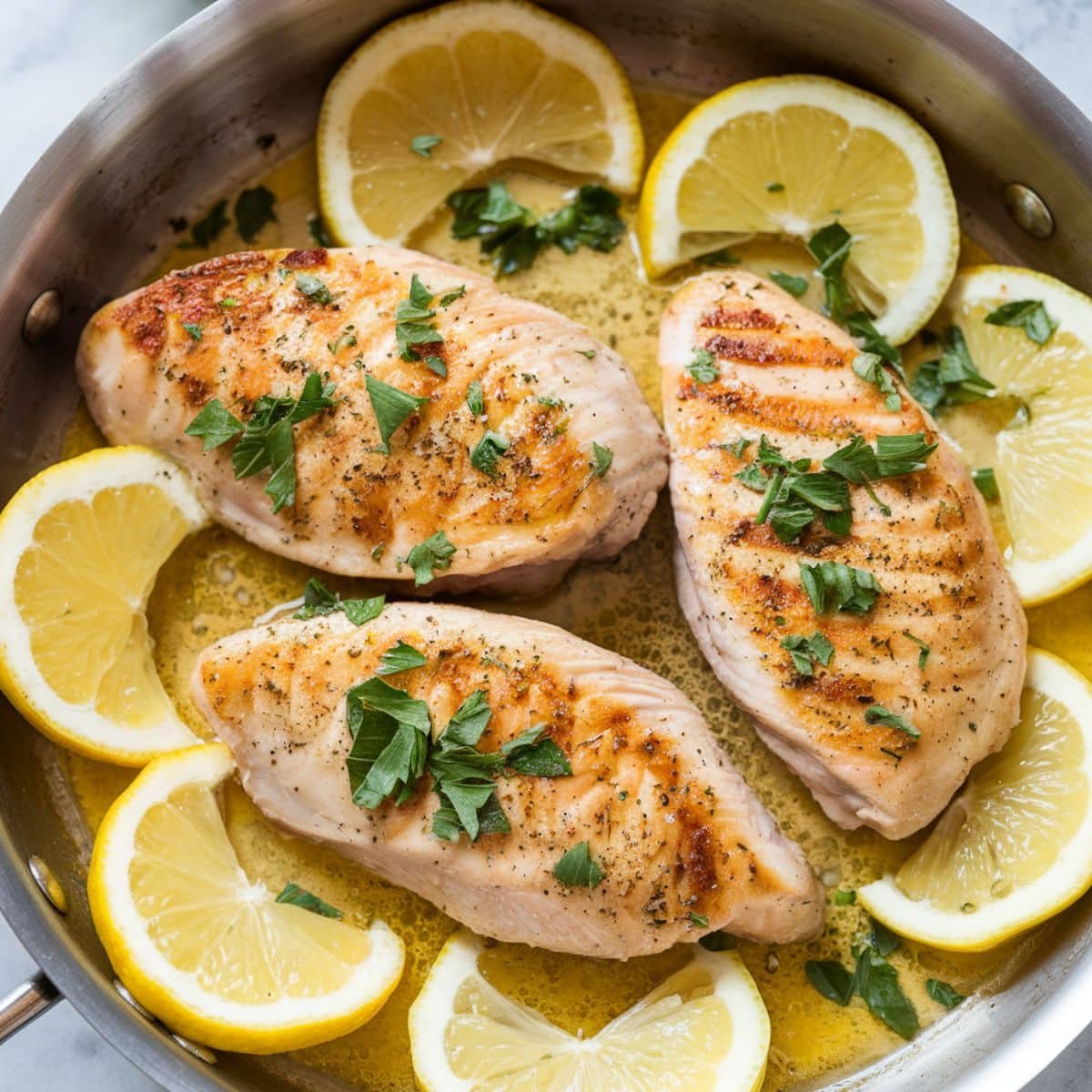 Freshly cooked Lemon Pepper Chicken Breasts garnished with parsley and served in a skillet with lemon slices, showcasing a golden, juicy, and flavorful dish. Perfect for a quick and easy dinner recipe.