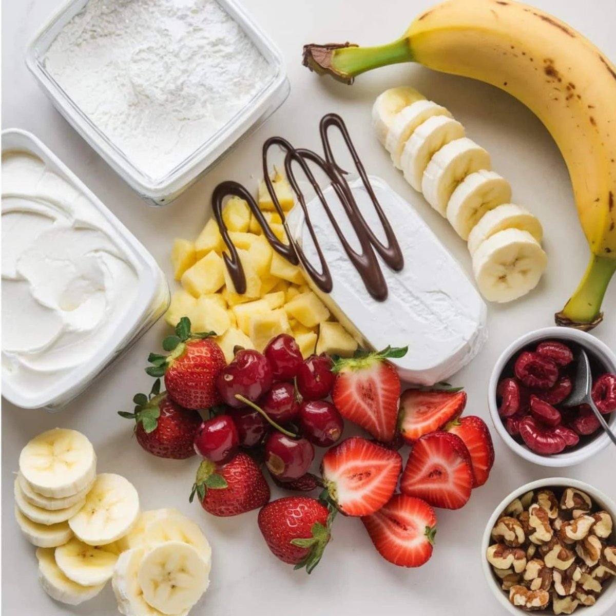 Fresh Ingredients for the Ultimate Banana Split Cake Recipe – A delicious no-bake dessert featuring bananas, strawberries, cherries, pineapple, cream cheese, whipped topping, chocolate drizzle, and crunchy nuts. Perfect for a refreshing and easy homemade treat!