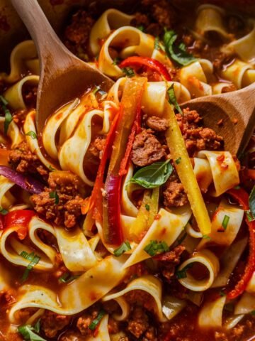 Italian Drunken Noodles Recipe – A vibrant and hearty dish featuring wide pappardelle pasta tossed in a rich tomato-based sauce with Italian sausage, sautéed bell peppers, red onions, and fresh basil. The bold flavors are enhanced with garlic, spices, and a splash of balsamic vinegar, creating a comforting and flavorful pasta dish. Perfect for an easy, rustic Italian-inspired meal.