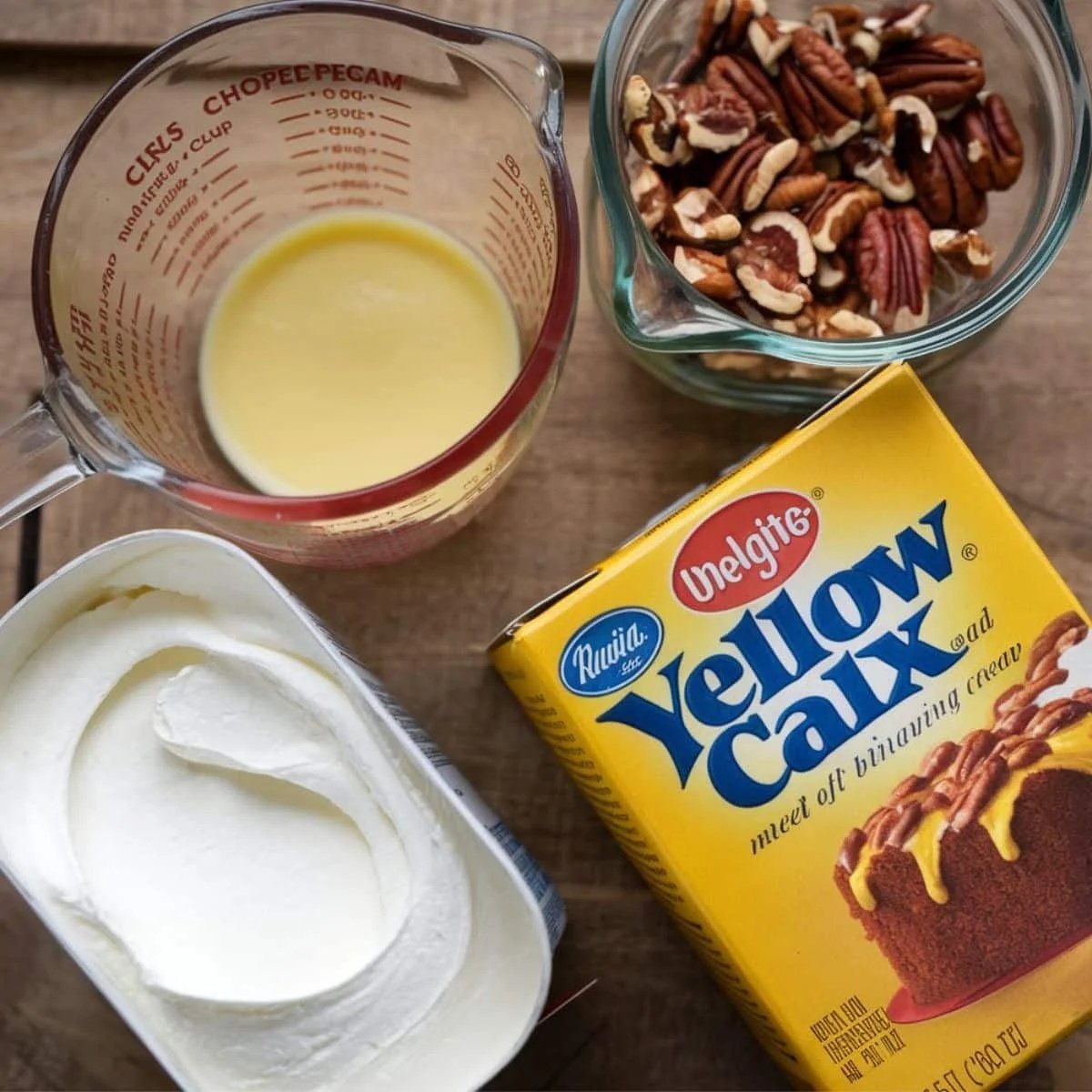 Ingredients for the Pumpkin Dump Cake Recipe topping, including yellow cake mix, melted butter, chopped pecans, and whipped topping, arranged on a rustic wooden surface. A simple and delicious way to create a buttery, crunchy dessert.