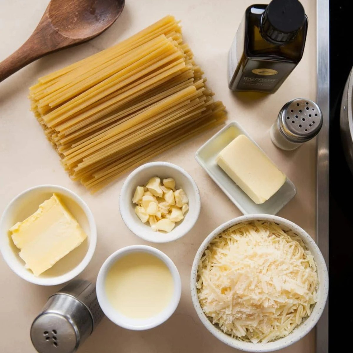 A top-down view of essential ingredients for a Truffle Pasta Recipe, including spaghetti, butter, garlic, Parmesan cheese, truffle oil, and cream, arranged on a kitchen counter. Perfect for making a rich, creamy, and indulgent truffle-infused pasta dish.