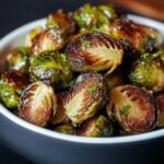 Homemade crispy Brussels sprouts, roasted to golden brown with caramelized edges, halved and topped with fresh parsley in a ceramic bowl.