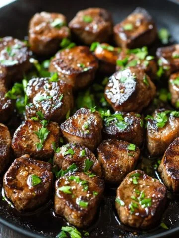 Juicy garlic butter steak bites seared in a cast iron skillet, topped with fresh parsley and glistening with rich garlic butter.