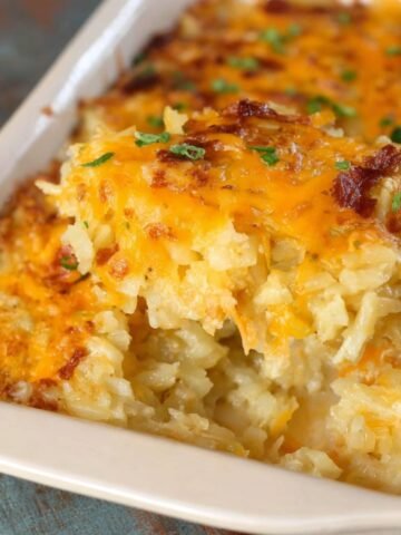 Homemade hashbrown casserole with a golden, cheesy top and creamy potato filling, served in a ceramic baking dish