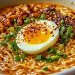 Homemade ramen noodles with spicy broth, soft-boiled egg, grilled chicken, green onions, and chili flakes.
