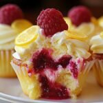 Raspberry Lemon Cupcakes with cream cheese frosting, raspberry filling, fresh raspberry, and lemon slice on top; one cupcake is cut open to show the jam center.