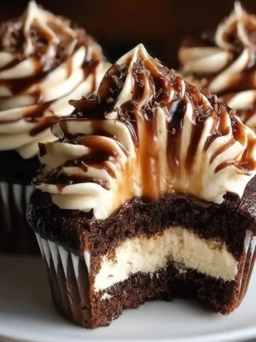 Homemade chocolate coffee cream cupcakes with creamy filling, espresso frosting, and chocolate drizzle, shown close-up on a plate.