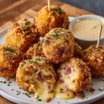 Easy Chicken Cordon Bleu Bites Recipe with melted cheese and ham inside, topped with parsley and served with Dijon dipping sauce on a white plate.