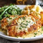 Longhorn Steakhouse Parmesan Chicken topped with melted cheese and parsley, served with green beans and roasted potatoes on a white plate.