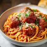 Spaghetti and Meatballs topped with meatballs in rich tomato sauce, sprinkled with Parmesan and fresh parsley.