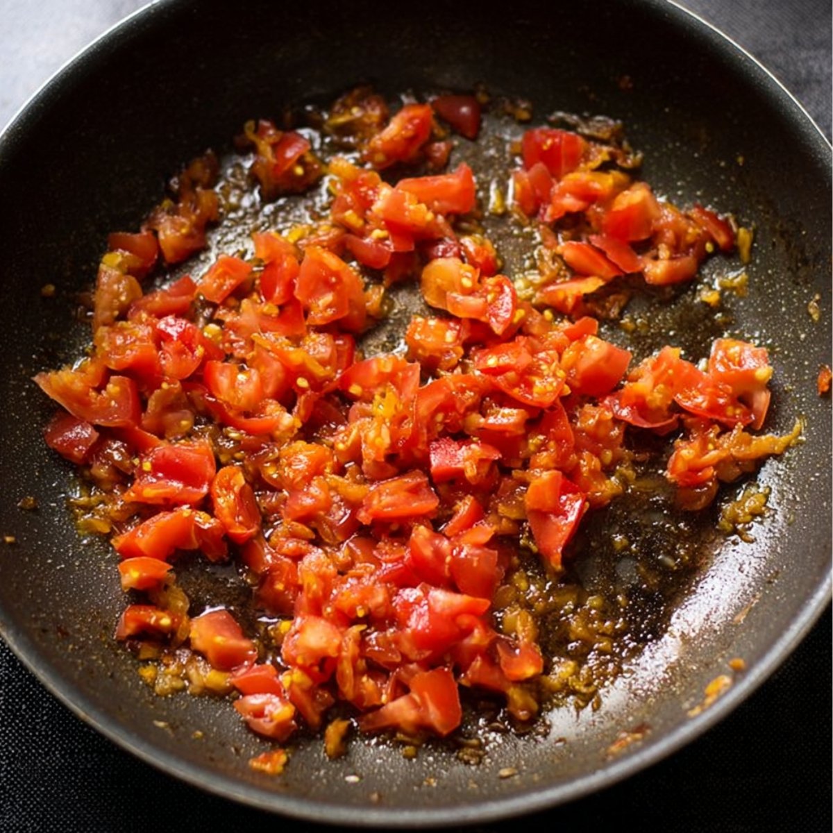 Toss in the chopped tomatoes and cook them down until they soften and the oil begins to separate from the mixture, about 3 to 4 minutes.