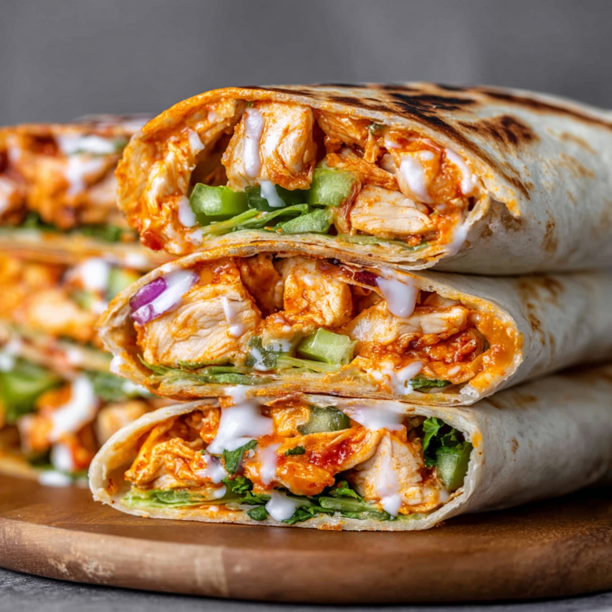 Stacked buffalo chicken wraps with shredded chicken, celery, and ranch sauce, wrapped in soft tortillas.