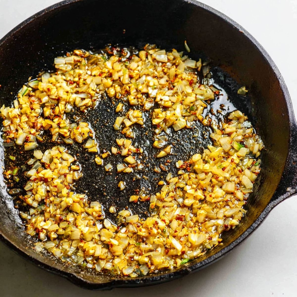 Add the remaining tablespoon of oil to the same skillet. Toss in the chopped onion, jalapeño, ginger, and garlic. Stir everything around and let it cook for about 5 minutes until the onion turns soft and translucent and your kitchen starts smelling incredible.