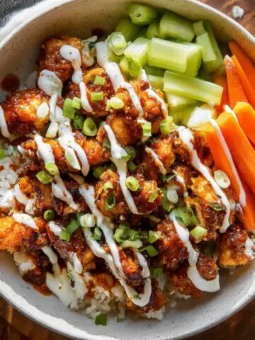 Homemade Buffalo Chicken Bowls with ranch drizzle, green onions, celery, and carrots.