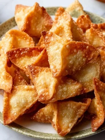 A plate of golden, crispy crab rangoons with perfectly browned edges, arranged neatly.
