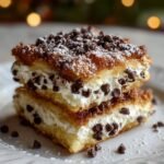 Ricotta Cannoli Squares stacked on a white plate, filled with creamy ricotta and mini chocolate chips, dusted generously with powdered sugar.