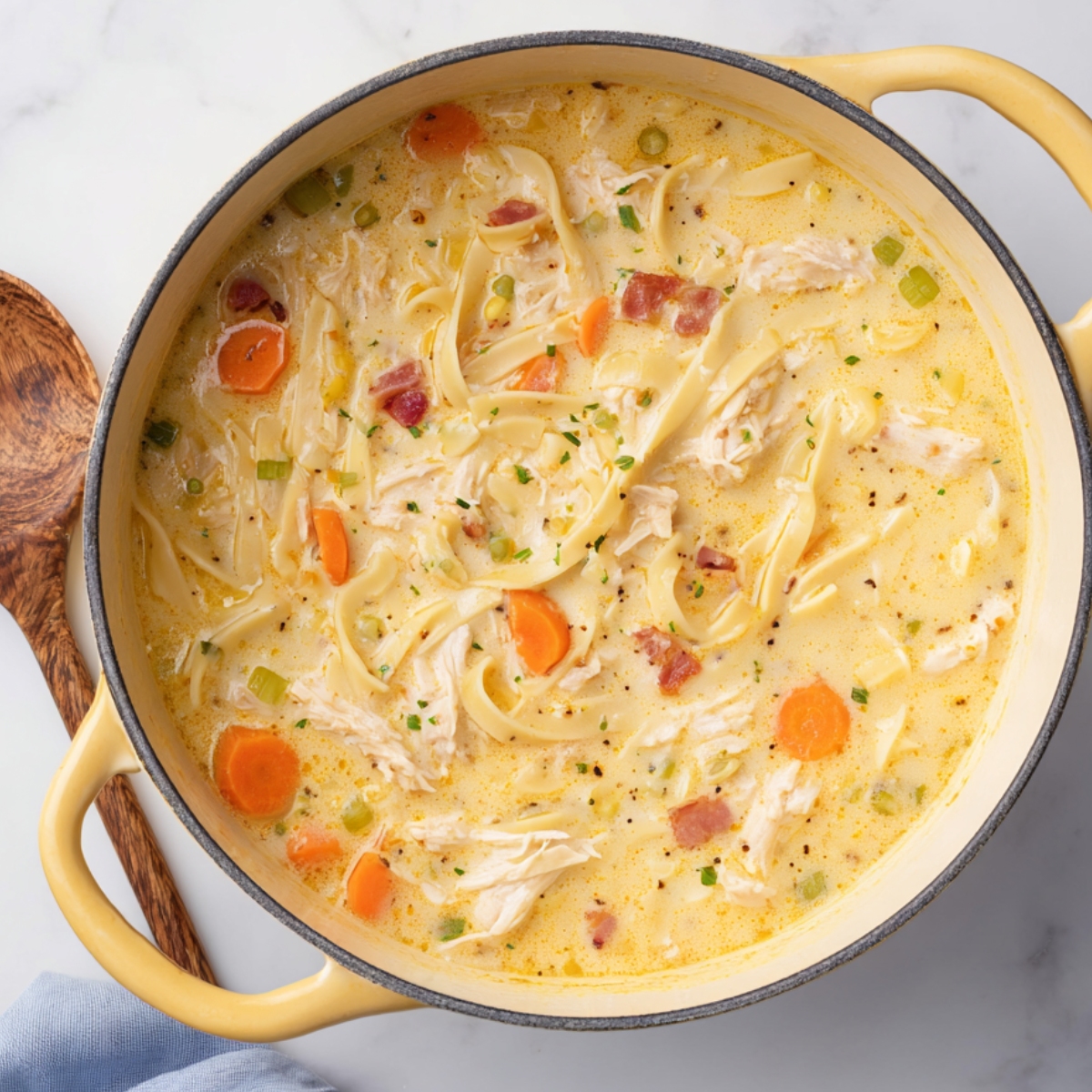 Stir in the uncooked egg noodles and shredded cheddar cheese. Keep the heat on low and cook for 5 to 6 more minutes, stirring now and then, until the noodles are tender and the cheese has melted completely.