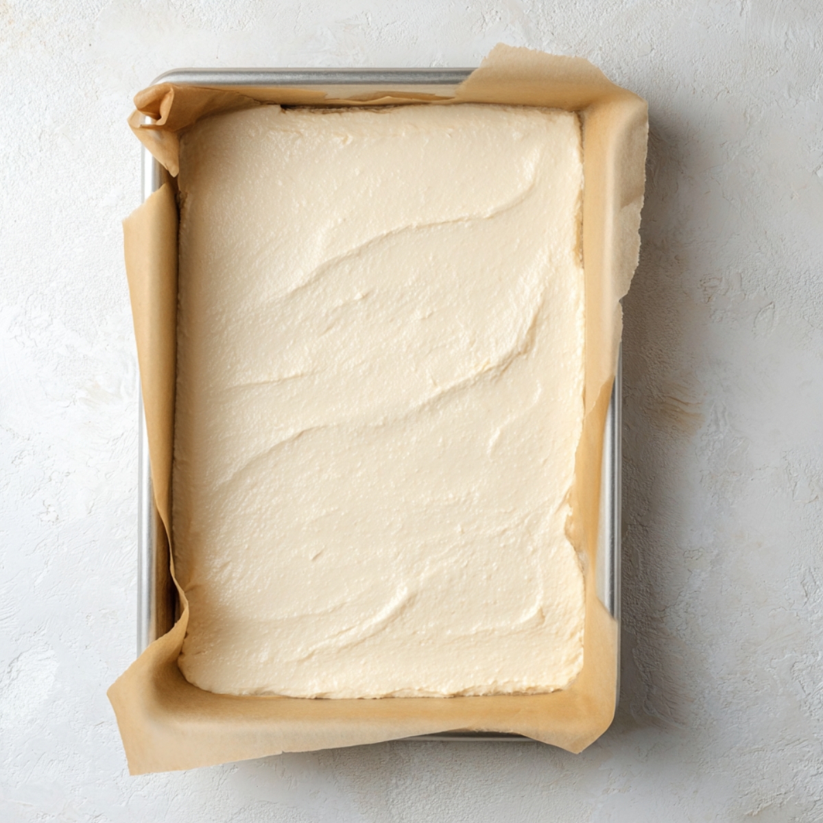 Swiss roll sponge batter spread evenly in a parchment-lined baking pan