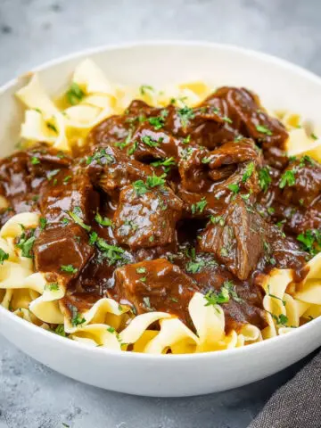 Tender Beef and Noodles covered in thick brown gravy, garnished with parsley