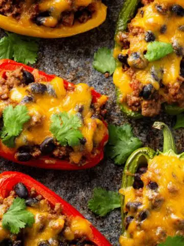A delicious close-up of Bell Pepper Nachos halves stuffed with seasoned ground beef, black beans, corn, and melted cheese, garnished with fresh cilantro.