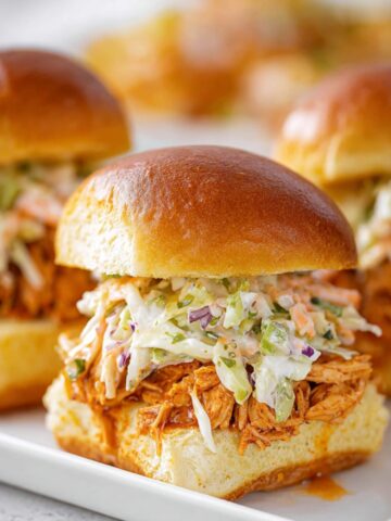 A plate of Buffalo Chicken Sliders topped with creamy coleslaw.