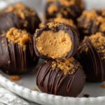 Butterfinger Balls with chocolate drizzle and crushed candy on a plate.