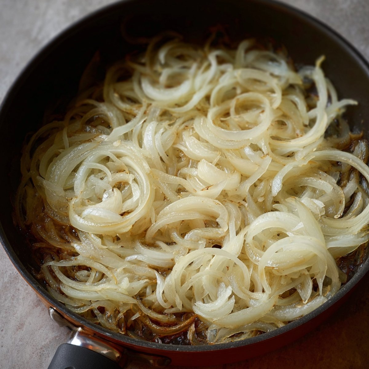 Onions slowly caramelizing in a pan, turning golden and sweet, ready to be added to dishes.