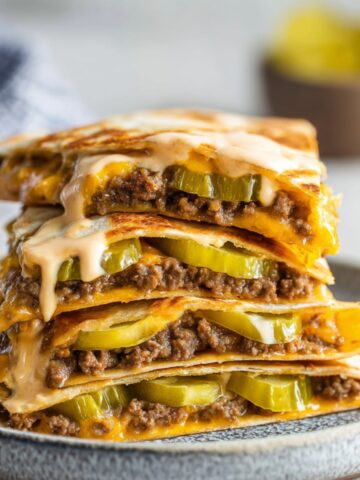 Cheeseburger Quesadillas with melted cheese, ground beef, pickles, and special sauce, served on a plate.