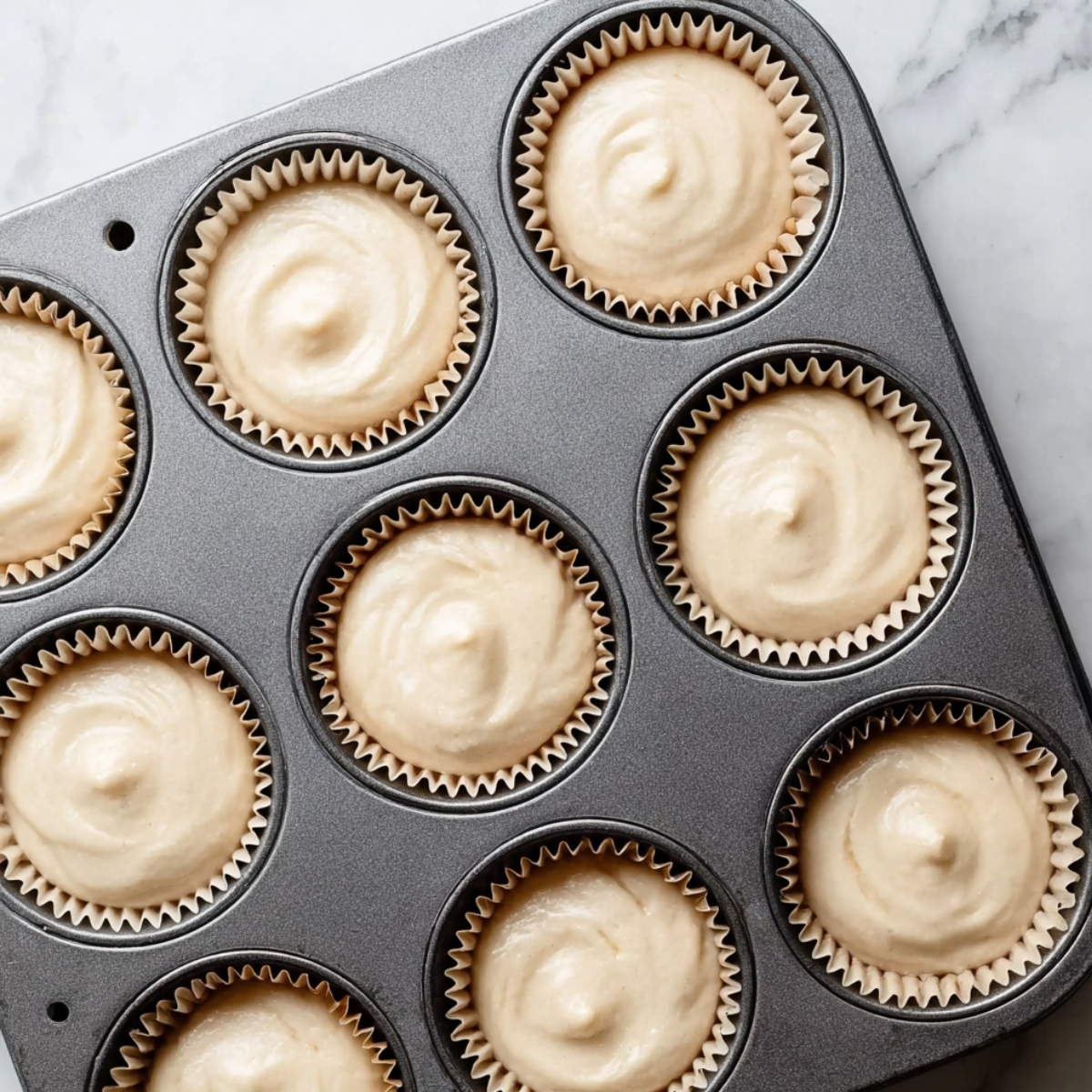 Cupcake batter portioned into lined muffin tin before baking