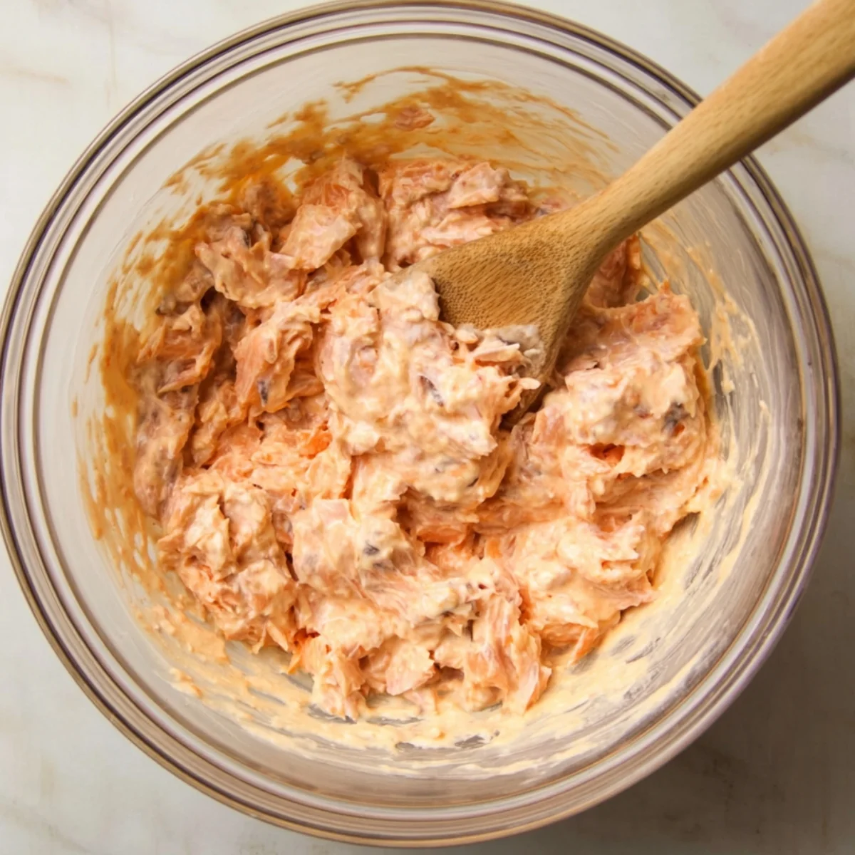 In a large bowl, mix the flaked salmon with softened cream cheese, mayonnaise, and sriracha sauce. Stir until everything is creamy and well combined. The mixture should be spreadable and slightly spicy.