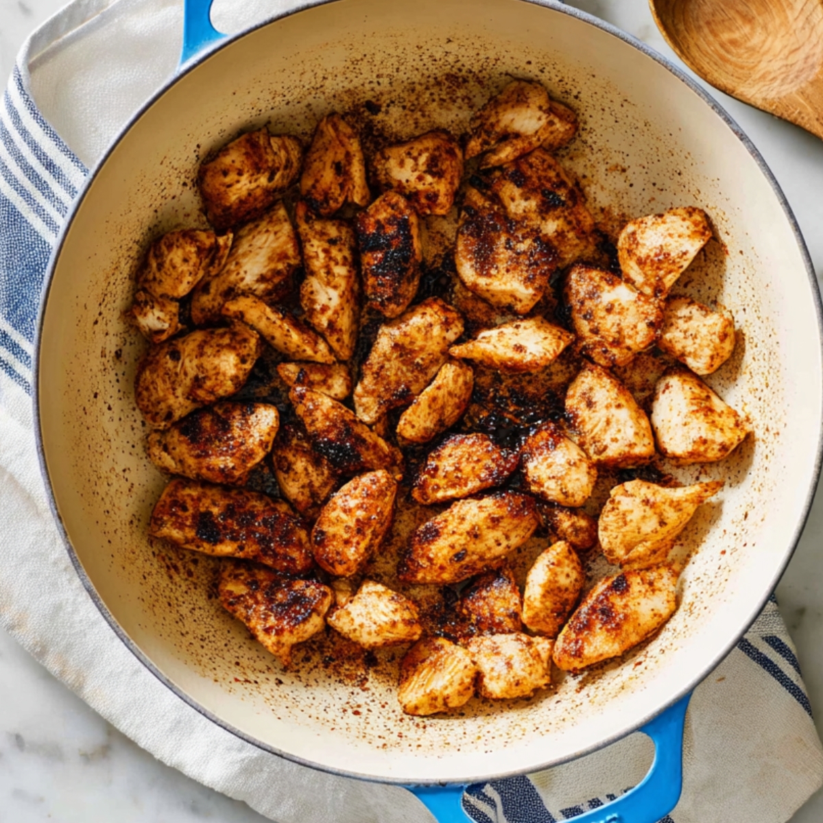 Cajun-seasoned chicken pieces seared in a skillet until golden brown and fully cooked.
