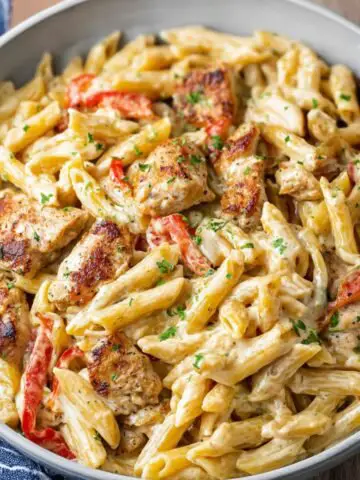 Creamy Cajun chicken pasta with penne, bell peppers, and parsley served in a bowl.
