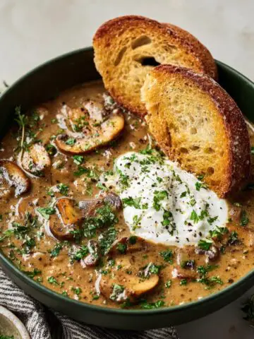 Creamy Hungarian Mushroom Soup with sliced mushrooms, sour cream, herbs, and toasted bread slices.
