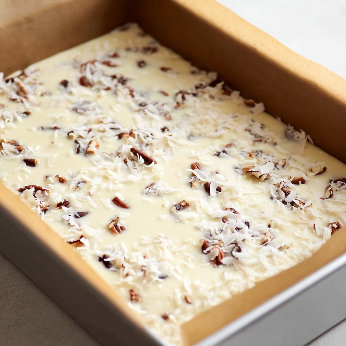 Pour the sweetened condensed milk slowly and evenly over the top of all the layered ingredients. It might not look like enough at first, but it'll spread as it bakes.