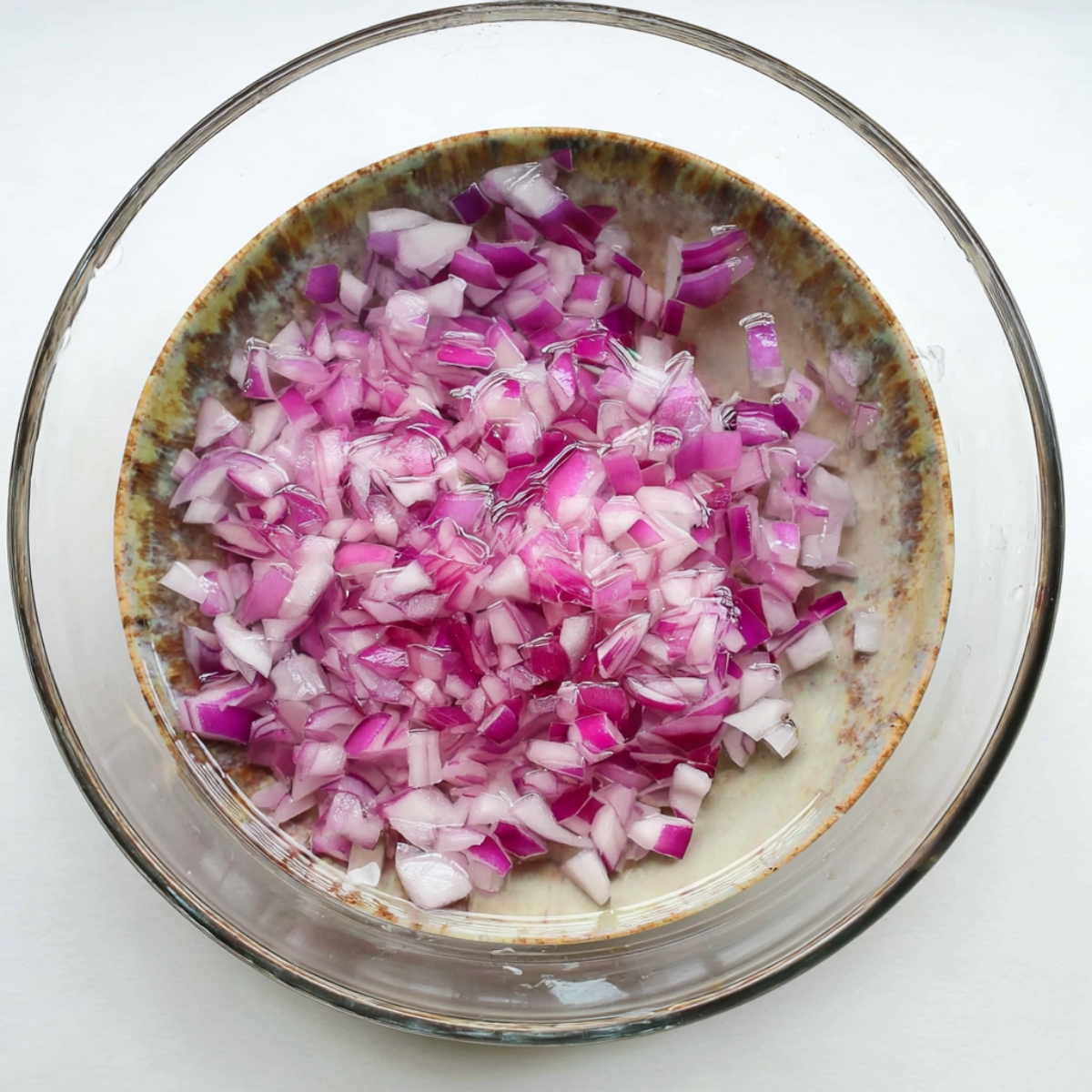 In a mixing bowl, add the diced red onion and sprinkle with kosher salt. Pour 2 tablespoons of olive oil and the red wine vinegar over the top. Let this sit for 5 to 10 minutes so the onion softens and the flavors blend together.