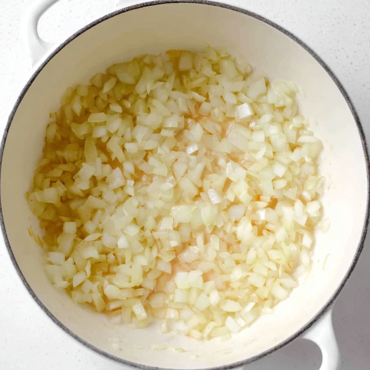 Chopped onions softening in a pot, lightly cooked and turning translucent.