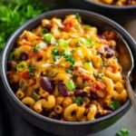 Bowl of Vegetarian Chili Mac topped with melted cheddar cheese, green onions, and parsley