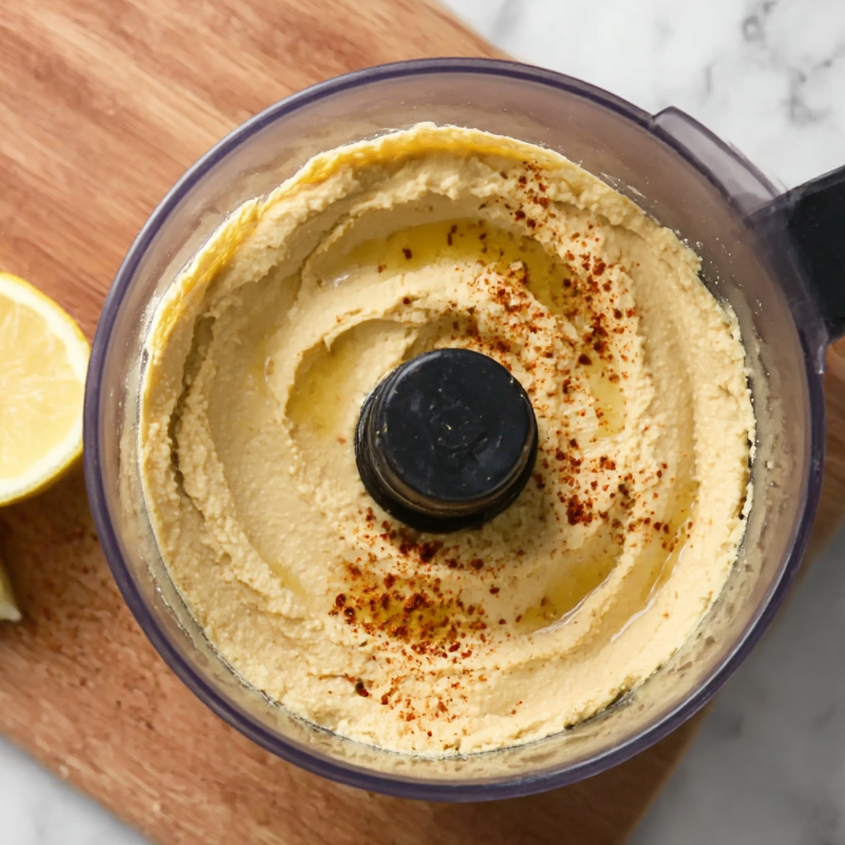 Smooth and creamy hummus blended to perfection in a food processor, with olive oil and paprika sprinkled on top for added flavor.