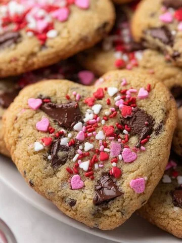 Heart Shaped Chocolate Chip Cookies decorated with pink, red, and white sprinkles, featuring gooey chocolate chunks.