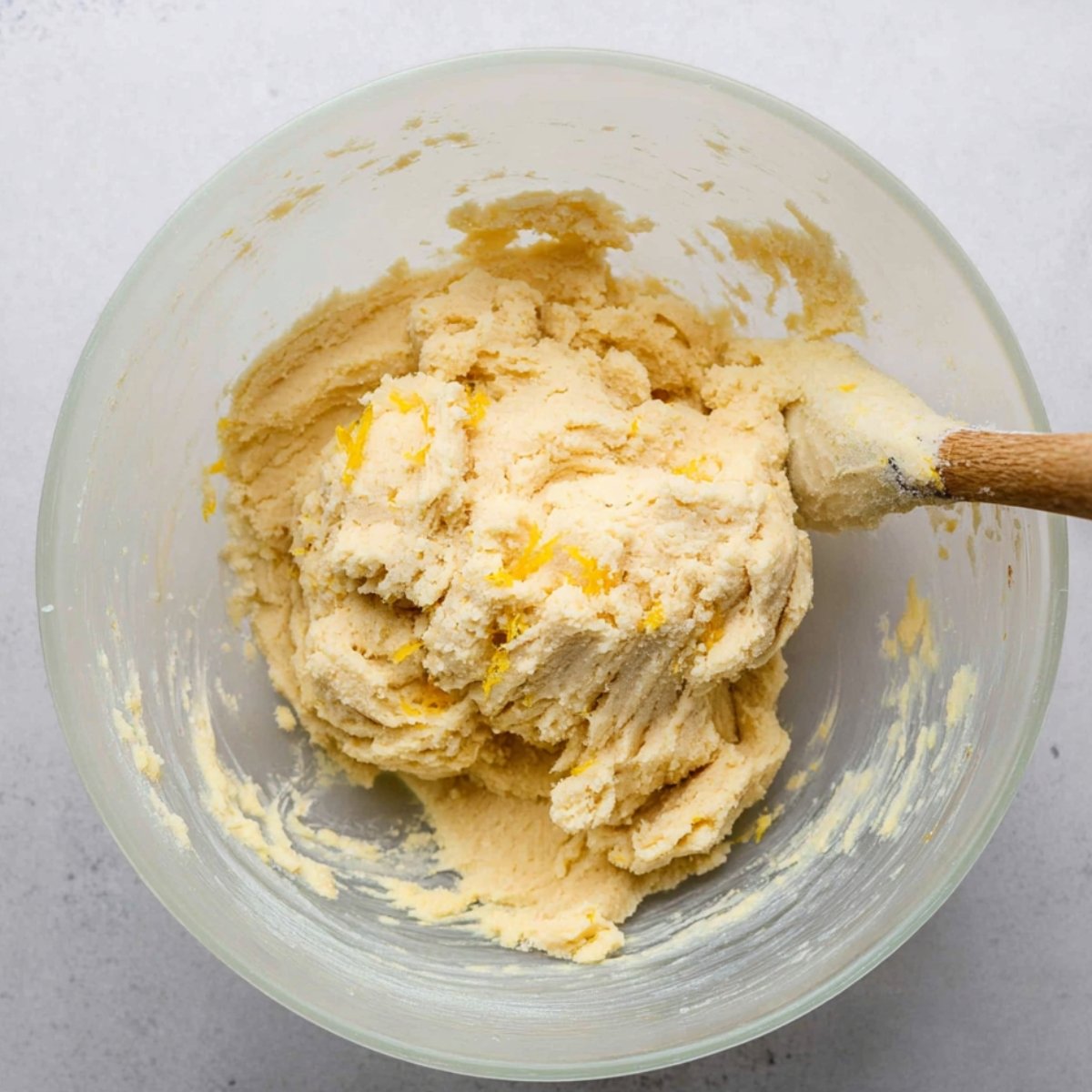 A bowl of lemon shortbread dough, mixed with butter, sugar, and lemon zest, ready to be rolled out.