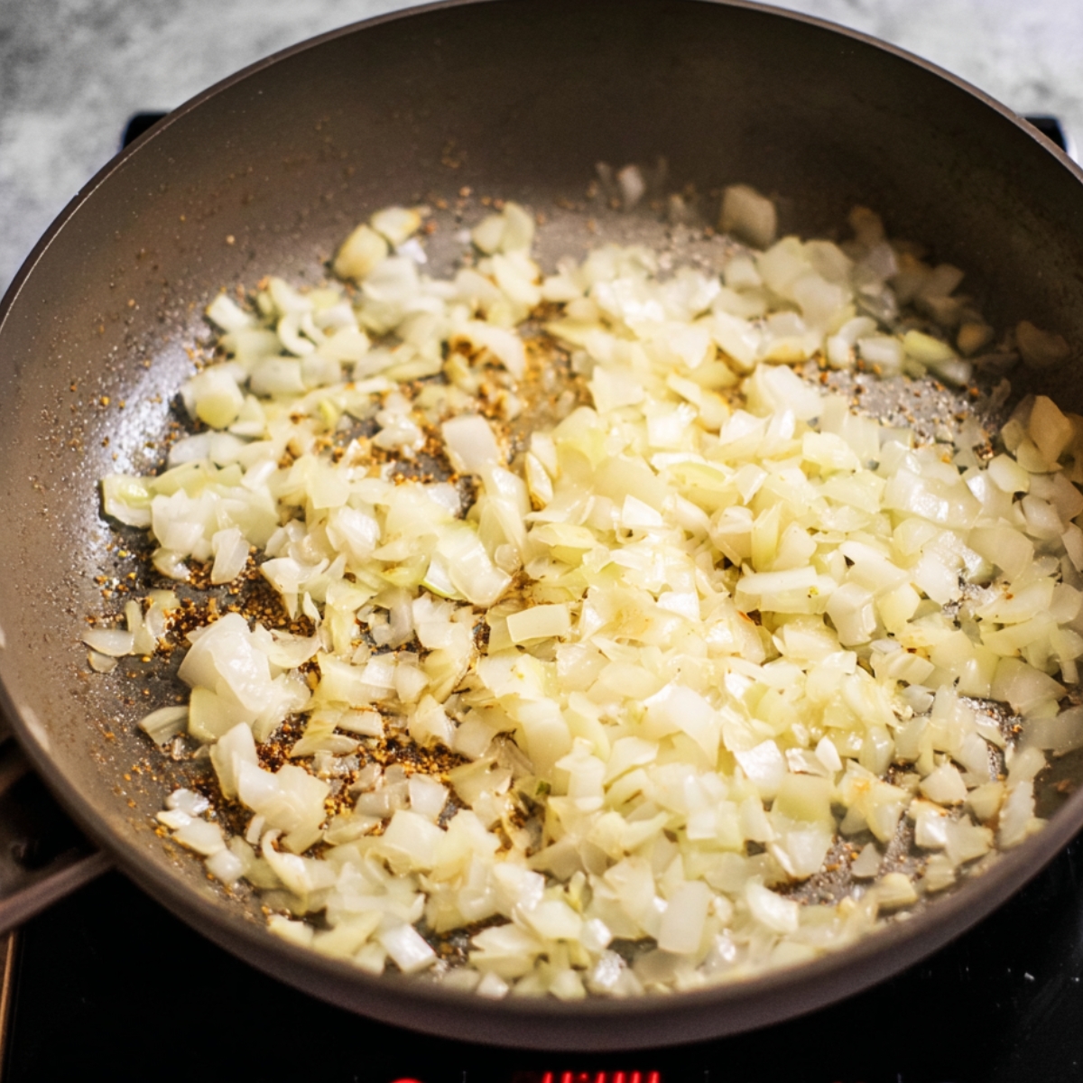 Chopped onions sautéing with spices in a pan.