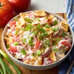 Creamy Tomato Cracker Salad with eggs, green onions, and crushed crackers, garnished with black pepper.