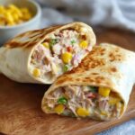 A close-up of a delicious Tuna Melt Wrap, golden and crispy on the outside, with a filling of tuna, corn, and vegetables.