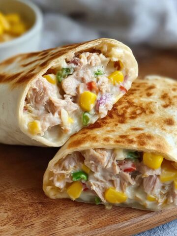 A close-up of a delicious Tuna Melt Wrap, golden and crispy on the outside, with a filling of tuna, corn, and vegetables.