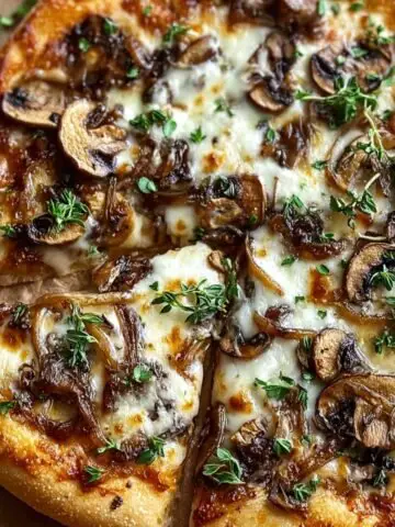 A delicious White Mushroom Pizza topped with caramelized onions, mozzarella cheese, and fresh thyme, with a slice pulled out.